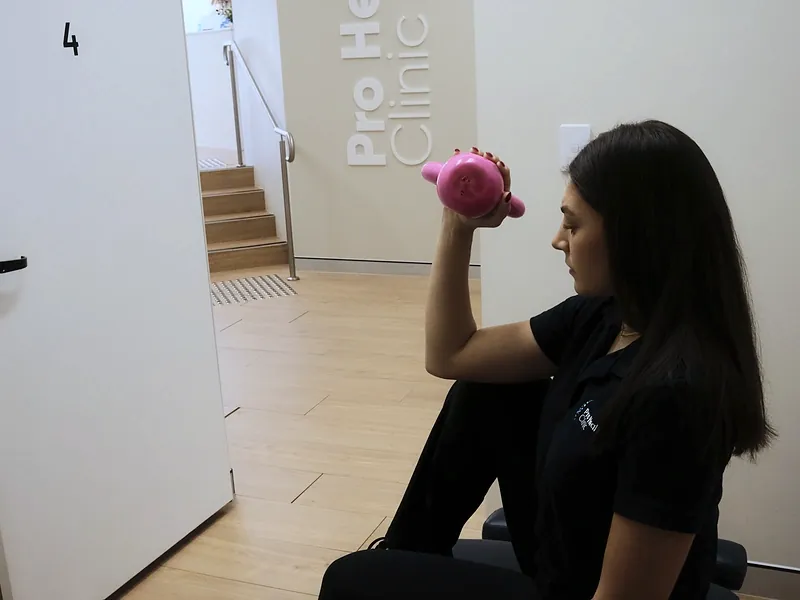 Practitioner demonstrating a strengthening exercise with a dumbbell