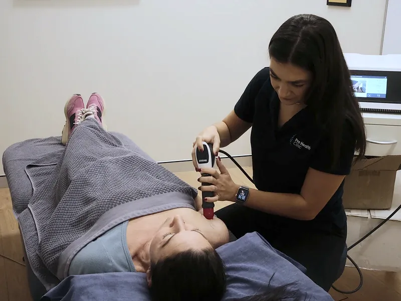 Shockwave therapy handpiece applied to a patient’s shoulder