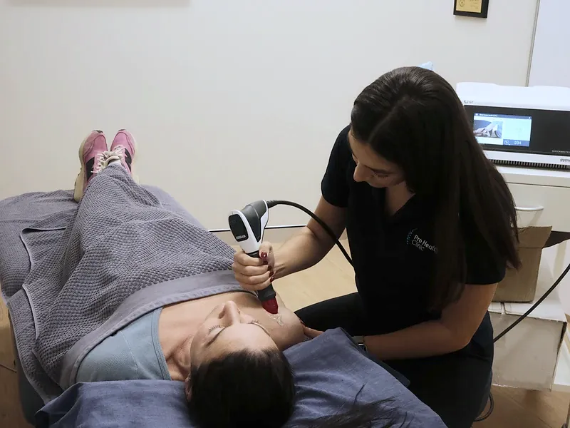 Practitioner operating the shockwave therapy unit during treatment
